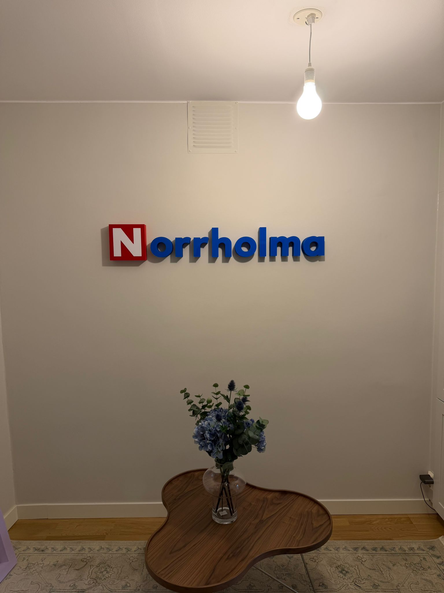 Frigolitskylt med plexifront monterad på kontorsvägg hos Norrholm, tillverkad av JM Printsolutions i Stockholm