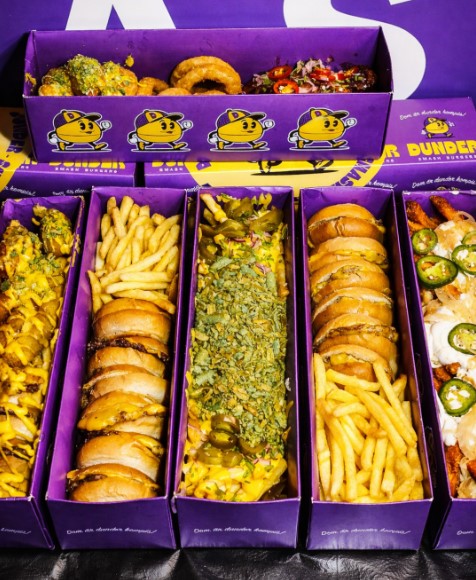 Flatboxar med miniburgare, pommes och tillbehör i tryckta lådor från Dunder Smash Burgers